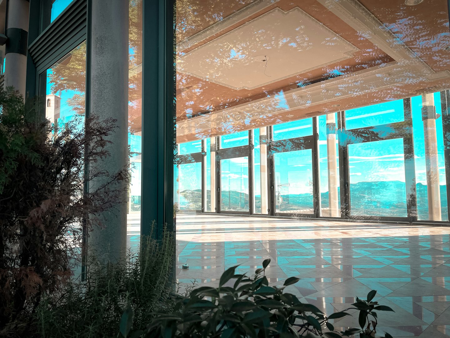 Empty room with floor-to-ceiling windows overlooking mountains.