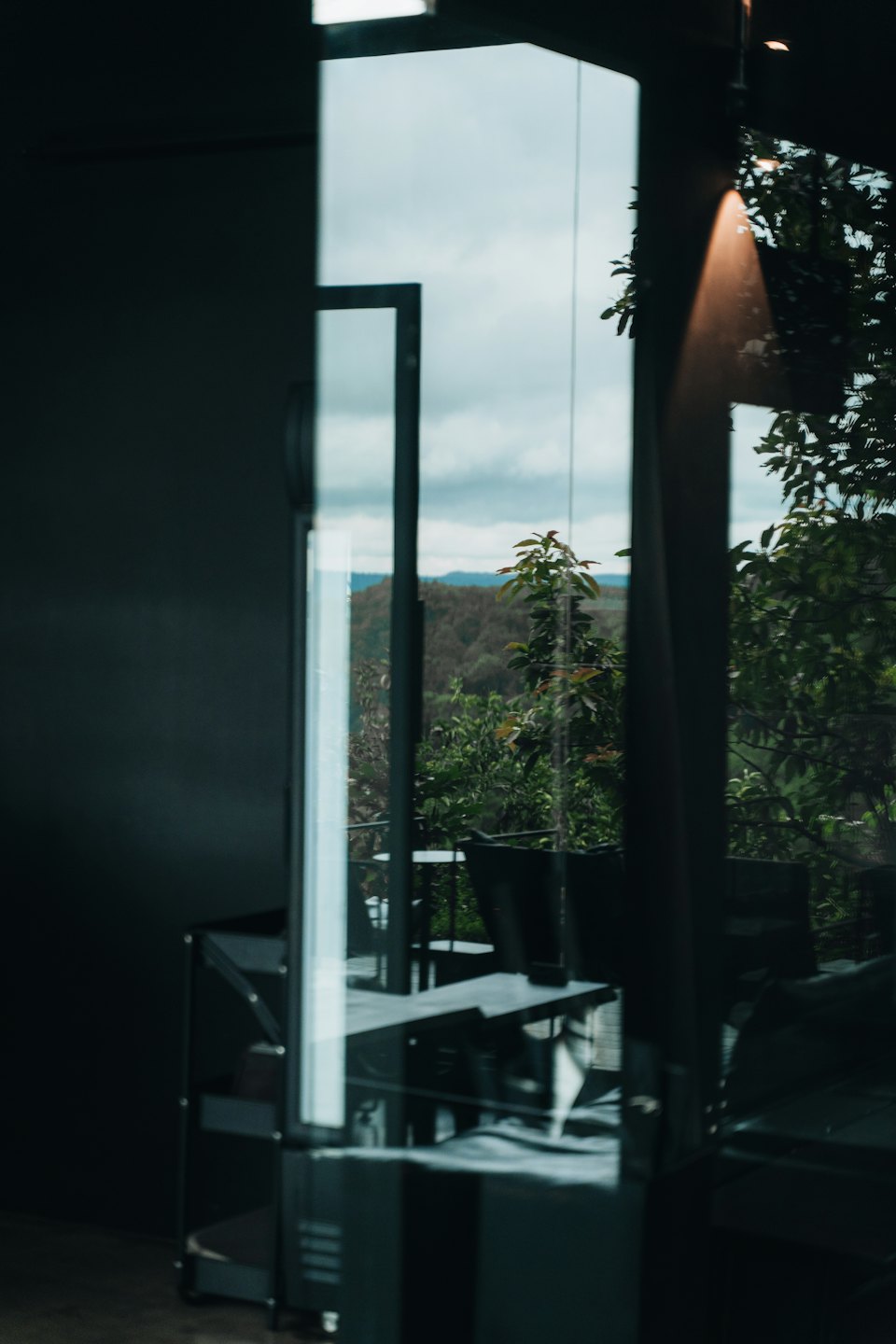 Green mountains are visible through a large glass window wall.