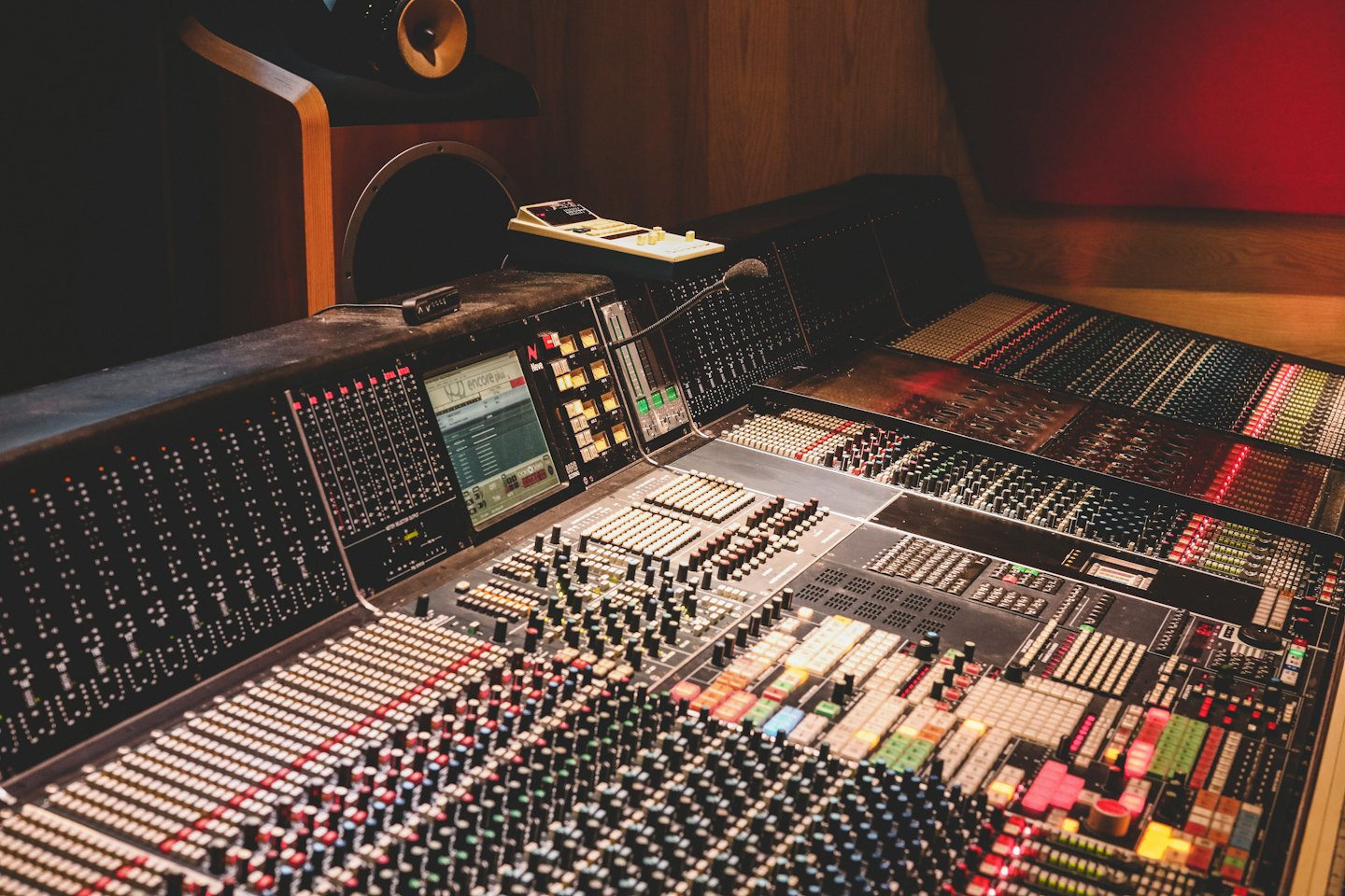 Audio mixing console with faders and knobs in a recording studio.